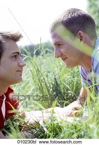 Stock Image - romance in the grass between two gay men (20-25 years). Fotosearch