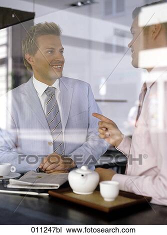 Stock Image - smiling businessman listening to colleague´s explanations. Fotosearch