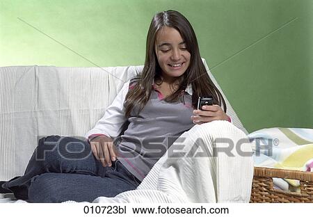 smiling girl looking at display of mobile phone View Large Photo Image Stock Image - smiling girl looking at display of mobile phone. Fotosearch