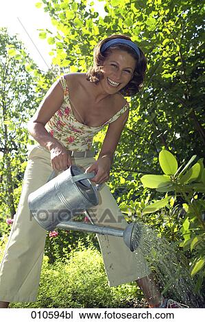 smiling woman in garden watering some plants View Large Photo Image Stock Image - smiling woman in garden watering some plants. Fotosearch