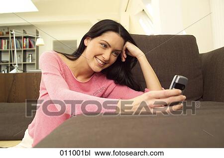 Smiling woman watching display of mobile phone View Large Photo Image Stock Image - Smiling woman watching display of mobile phone. Fotosearch