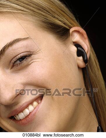 Stock Image - Smiling woman wearing earphone. Fotosearch