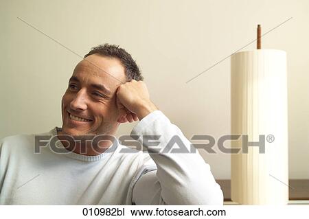 Smiling young man sitting beside lamp View Large Photo Image Stock Image - Smiling young man sitting beside lamp. Fotosearch
