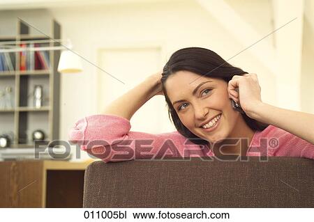 Smiling young woman using cellphone at home View Large Photo Image Stock Image - Smiling young woman using cellphone at home. Fotosearch