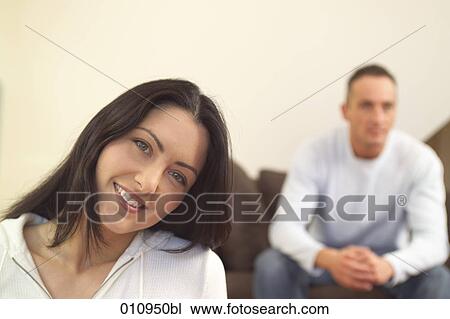 Stock Image - Smiling young woman with boyfriend sitting in the back. Fotosearch
