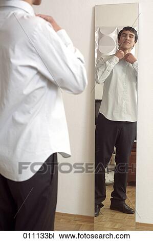 Teenage boy putting on a white shirt in front of the mirror View Large Photo Image Stock Image - Teenage boy putting on a white shirt in front of the mirror. Fotosearch