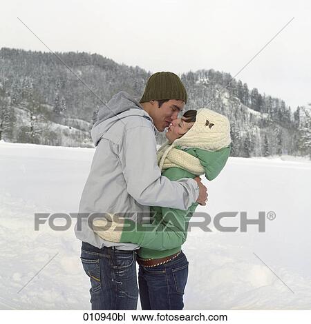 Stock Image - teenage couple kissing each other in the snow. Fotosearch