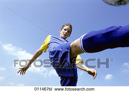 Stock Image - teenage football player kicking the ball. Fotosearch