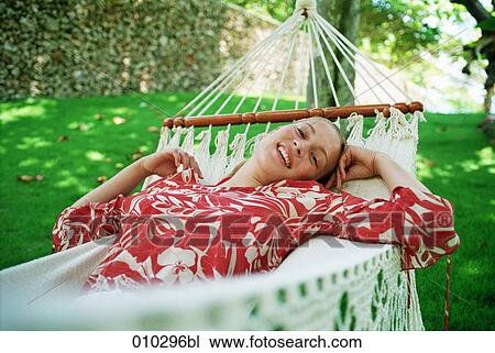Stock Image - teenage girl (16-19 years) enjoying her time in a hammock. Fotosearch
