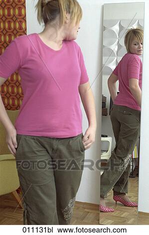 Stock Image - Teenage girl checking her figure in the mirror. Fotosearch