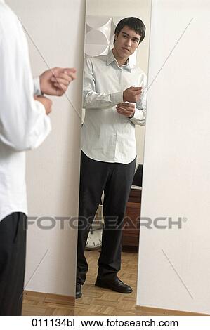 Stock Image - Teenager buttoning the sleeves of his white shirt. Fotosearch