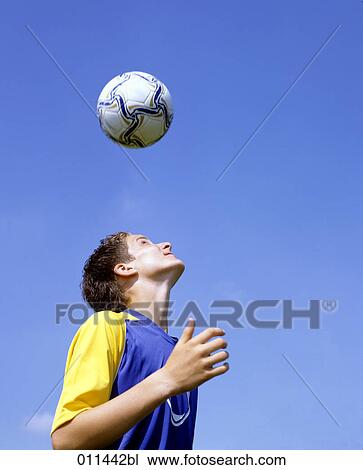 Stock Image - teenager exercising headers. Fotosearch