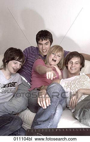 Stock Image - Teenagers watching tv, one girl pointing towards screen. Fotosearch