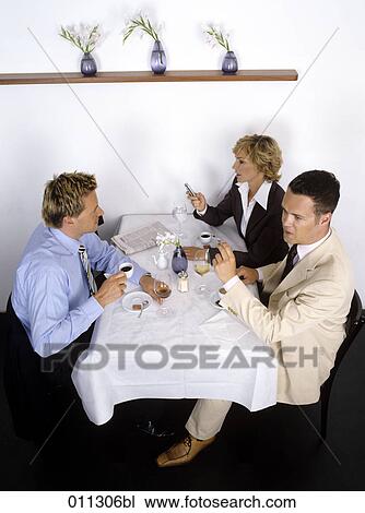 Stock Image - three business people at business lunch, one holding a credit card ready to pay. Fotosearch