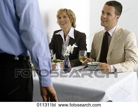 two business people smiling at person near their table View Large Photo Image Stock Image - two business people smiling at person near their table. Fotosearch