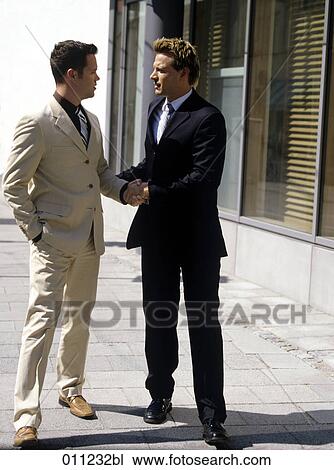 Stock Image - two businessmen shaking hands in the street. Fotosearch