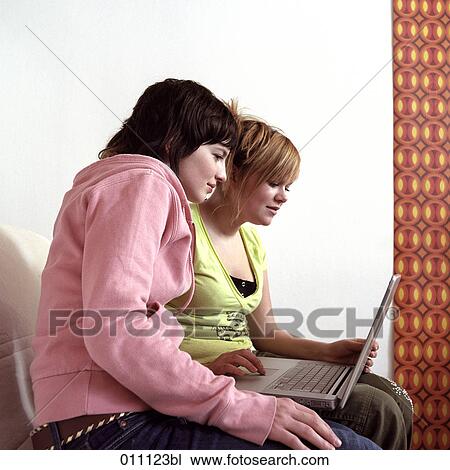 Two girlfriends looking at screen of laptop View Large Photo Image Stock Image - Two girlfriends looking at screen of laptop. Fotosearch
