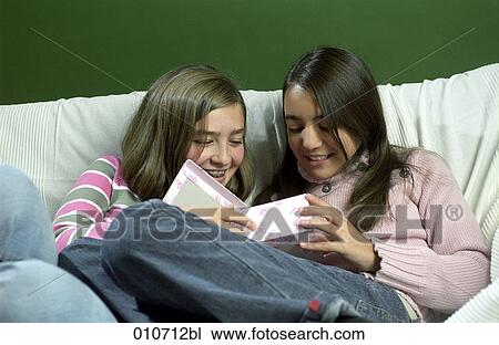 Stock Image - two girls looking at content of gift box. Fotosearch