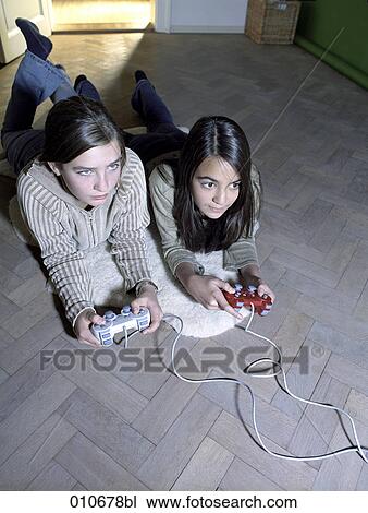 two girls lying on the floor enjoying a computer game View Large Photo Image Stock Image - two girls lying on the floor enjoying a computer game. Fotosearch
