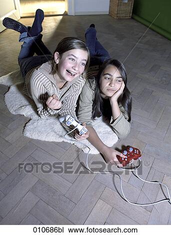 Stock Image - two girls playing computer game, one is winning while the other is looking disappointed. Fotosearch