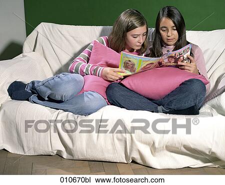 two girls sitting on a sofa reading a magazine View Large Photo Image Stock Image - two girls sitting on a sofa reading a magazine. Fotosearch