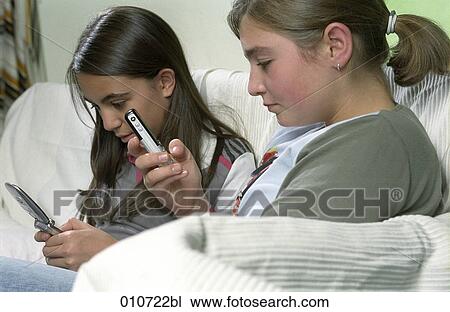 two girls writing text messages on mobile phones View Large Photo Image Stock Image - two girls writing text messages on mobile phones. Fotosearch