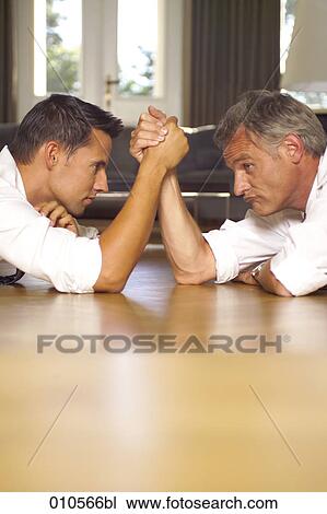 Stock Image - two men arm wrestling on the floor. Fotosearch