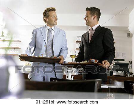 Stock Image - two men sharing a smile in a self-service restaurant. Fotosearch
