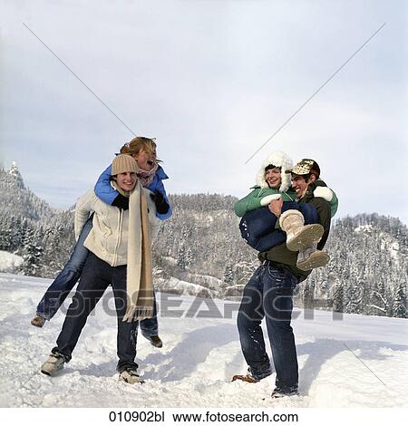 Stock Image - two teenage couples enjoying a day out in the snow. Fotosearch