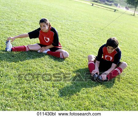 two teenagers in football gear doing stretching exercises View Large Photo Image Stock Image - two teenagers in football gear doing stretching exercises. Fotosearch