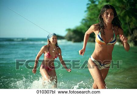 Stock Image - two women running out of the water. Fotosearch