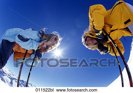 Stock Image - two women talking to each other having a break from skiing . Fotosearch