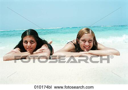 two young women lying in the sand and sunbathing View Large Photo Image Stock Image - two young women lying in the sand and sunbathing. Fotosearch