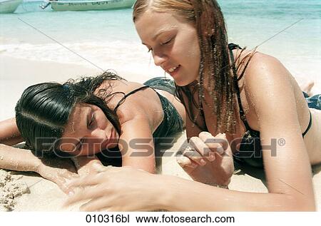 two young women lying in the sand at the beach relaxing and talking View Large Photo Image Stock Image - two young women lying in the sand at the beach relaxing and talking. Fotosearch