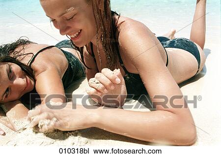 two young women lying in the sand at the beach relaxing and talking View Large Photo Image Stock Image - two young women lying in the sand at the beach relaxing and talking. Fotosearch