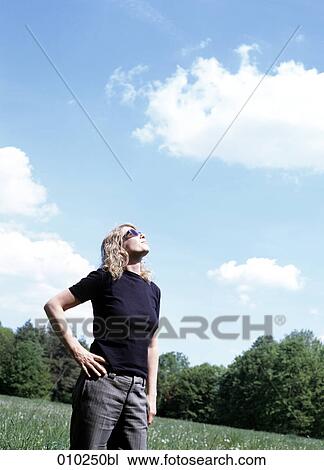 Stock Image - woman (35-40 years) looking up to the sun. Fotosearch