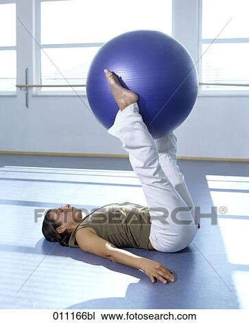Woman doing pilates training, holding blue ball with her legs View Large Photo Image Stock Image - Woman doing pilates training, holding blue ball with her legs. Fotosearch