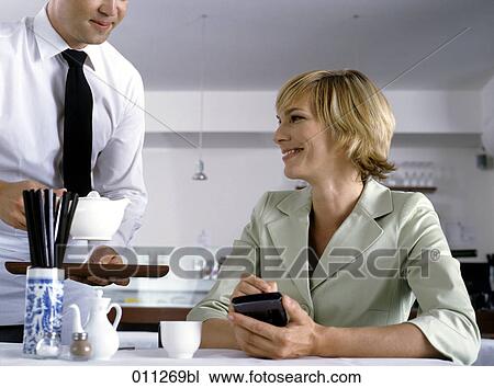 woman holding electronic organizer while being served in restaurant View Large Photo Image Stock Image - woman holding electronic organizer while being served in restaurant. Fotosearch