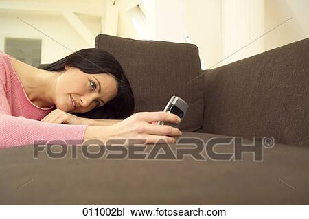 Woman lying on sofa and looking at display of cellphone View Large Photo Image Stock Image - Woman lying on sofa and looking at display of cellphone. Fotosearch