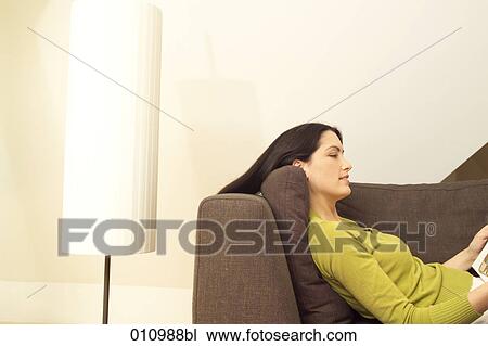 Woman lying on sofa reading a magazine View Large Photo Image Stock Image - Woman lying on sofa reading a magazine. Fotosearch