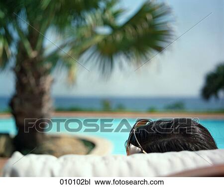 Stock Image - woman on deck chair sunbathing. Fotosearch