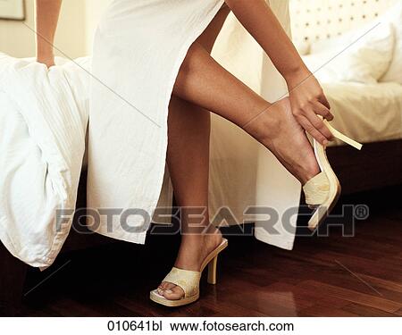 Stock Image - woman putting on shoes in a hotel room. Fotosearch