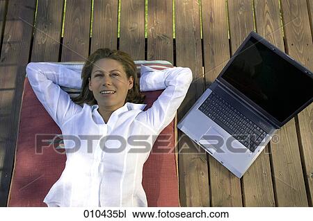 woman relaxing on her veranda, laptop beside her View Large Photo Image Stock Image - woman relaxing on her veranda, laptop beside her. Fotosearch