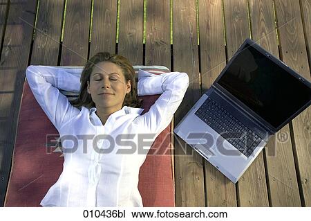 woman relaxing on her veranda, laptop beside her View Large Photo Image Stock Image - woman relaxing on her veranda, laptop beside her. Fotosearch