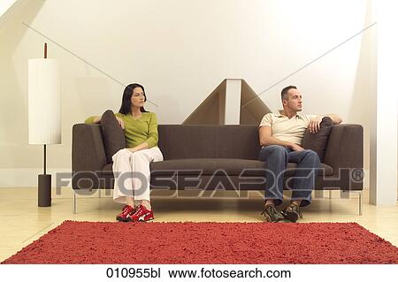 Woman sitting on couch looking suspiciously at her partner View Large Photo Image Stock Image - Woman sitting on couch looking suspiciously at her partner. Fotosearch