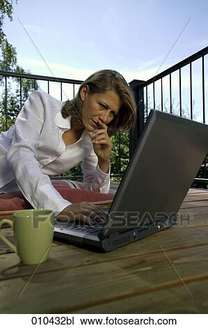 Stock Image - woman working with laptop on her veranda at home. Fotosearch