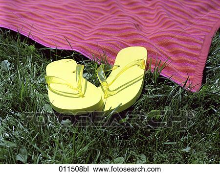 Stock Image - yellow flip flops lying in grass. Fotosearch