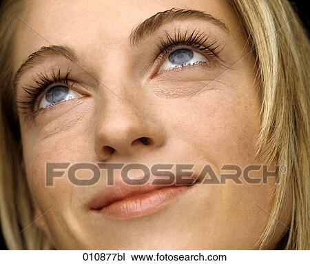 Stock Image - Young blonde woman looking up. Fotosearch