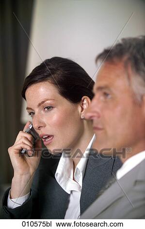 Stock Image - young businesswoman using a mobile phone during meeting. Fotosearch