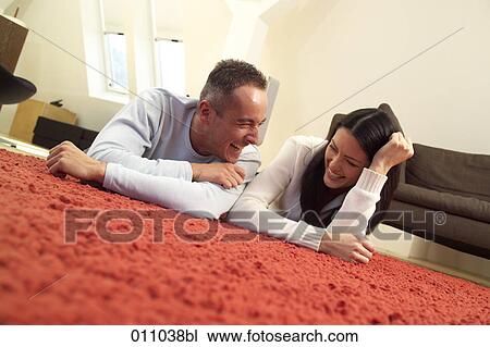 Young couple lying on the carpet having a laugh View Large Photo Image Stock Image - Young couple lying on the carpet having a laugh. Fotosearch